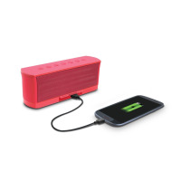 Czerwony głośnik Bluetooth iLuv MobiOut połączony czarnym kablem ze smartfonem, na którego ekranie widoczna jest ikona ładowania baterii na białym tle.