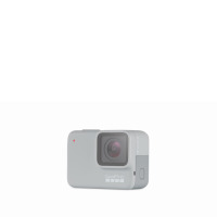 Kamera sportowa GoPro Hero 7 White w jasnoszarym kolorze, widok z przodu na obiektyw, czerwoną diodę sygnalizacyjną oraz boczną klapkę portów urządzenia.
