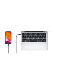 Czarny przewód Mophie USB-C do Lightning podłączony do iPhone'a z widocznym stanem naładowania baterii oraz do otwartego laptopa Apple MacBook na białym tle.