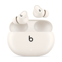 Słuchawki bezprzewodowe Beats Studio Buds + w kolorze kości słoniowej wraz z otwartym etui ładującym, na którym widnieje charakterystyczne logo marki Beats.