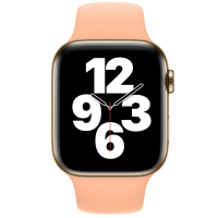 Złoty Apple Watch z silikonowym paskiem w kolorze Cantaloupe, widoczna tarcza z cyframi 12, 3, 6, 9 oraz wskazówkami zegara na czarnym tle.