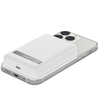 Biały powerbank Belkin Magnetic Wireless z rozkładaną podstawką przymocowany magnetycznie do srebrnego iPhone'a, widoczny port ładowania USB-C na obudowie.