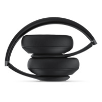 Czarne słuchawki Beats Studio Pro Wireless złożone w kompaktową formę, ukazujące profil konstrukcji z miękkimi nausznikami oraz wygiętym pałąkiem.