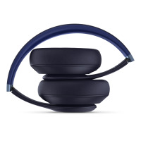 Granatowe słuchawki Beats Studio Pro Wireless złożone w kompaktowy sposób, ukazujące profil nauszników oraz wygięty pałąk z metalowymi elementami konstrukcji.