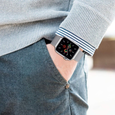 Srebrna bransoleta mediolańska Tech-Protect na nadgarstku mężczyzny w szarym swetrze, zestawiona z zegarkiem Apple Watch z aktywną tarczą informacyjną.