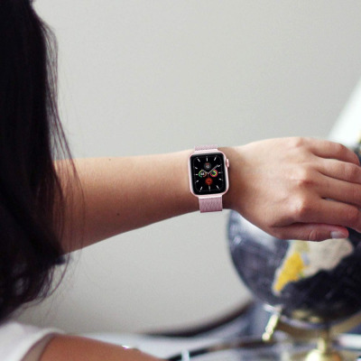 Różowa bransoleta mediolańska Tech-Protect na nadgarstku kobiety, zestawiona z zegarkiem Apple Watch z aktywną tarczą informacyjną w kolorze różowego złota.