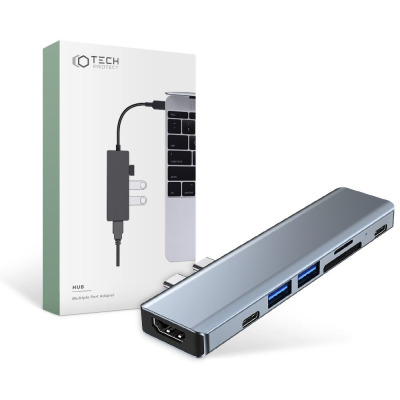 Szary adapter Tech-Protect V5-Hub 7in1 z wieloma portami obok opakowania z grafiką przedstawiającą podłączenie urządzenia do laptopa Apple MacBook.
