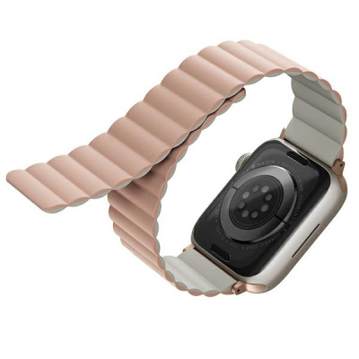 Dwustronny pasek UNIQ Revix w kolorze różowo-beżowym zamocowany do koperty Apple Watch, widok na spód zegarka z czujnikami tętna i oznaczeniami modelu.