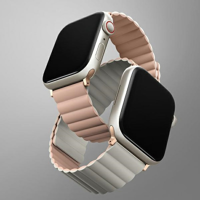 Dwustronny pasek UNIQ Revix w kolorze różowo-beżowym zamocowany do koperty Apple Watch, widok na spód zegarka z czujnikami tętna i oznaczeniami modelu.