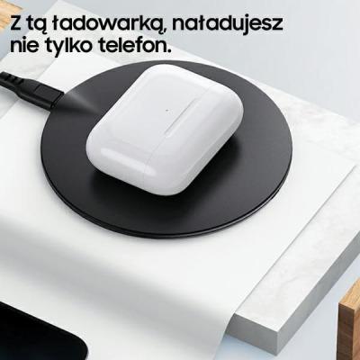Białe etui ładujące Apple AirPods leży na okrągłej czarnej ładowarce indukcyjnej Usams US-CD149, z napisem: Z tą ładowarką, naładujesz nie tylko telefon.
