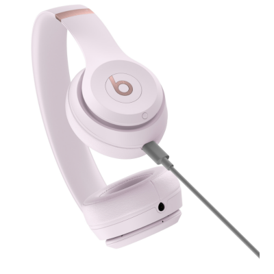 Słuchawki Beats Solo 4 Wireless w kolorze pudrowym z logo Beats, widoczne z podłączonym kablem ładującym USB-C oraz gniazdem audio 3,5 mm na obudowie.