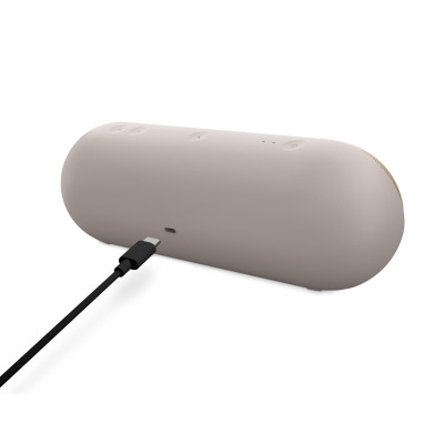 Głośnik Beats Pill w kolorze szampańskiego złota, widok na tylny panel z wpiętym kablem USB-C oraz przyciskami sterowania na górnej krawędzi obudowy.