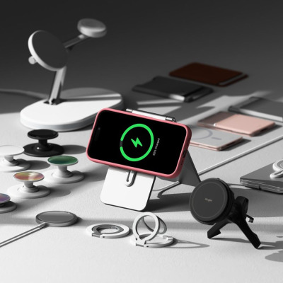 Różowe etui Ringke Silicone MagSafe na iPhone 16 umieszczone na podstawce ładującej, otoczone akcesoriami magnetycznymi i uchwytami na telefon.