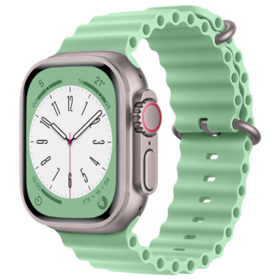 Pistacjowy pasek silikonowy Jinya do Apple Watch z perforowaną strukturą, założony na kopertę zegarka w kolorze tytanowym z widoczną cyfrową tarczą.